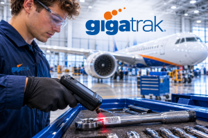 Aviation mechanic using a handheld barcode scanner to track a torque wrench in a commercial aircraft hangar, with GigaTrak branding prominently displayed. Barcode tool tracking.